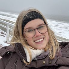 Lächelnde Frau mit Brille im Schneewetter an der Küste.