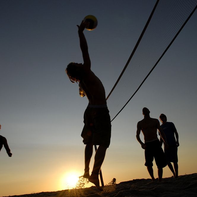 Junge Menschen spielen Beachvolleyball am Brandenburger Strand im Sonnenuntergang