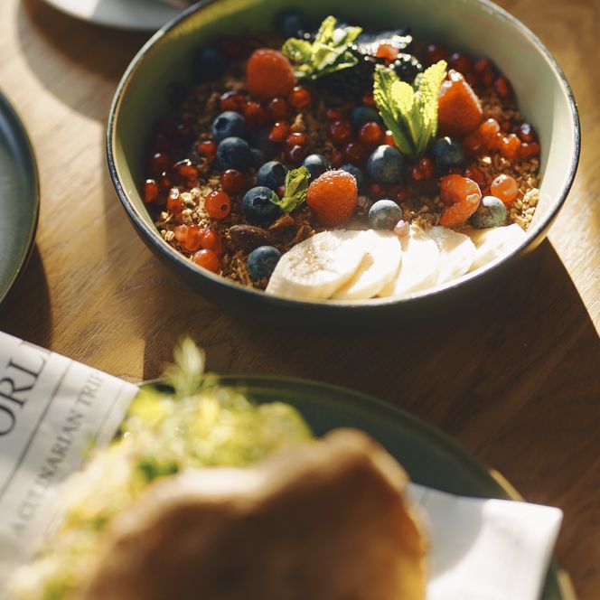 Frische Frühstücksbowl mit Beeren und Granola im Sonnenlicht Frühstücksbowl mit Beeren, Granola und Banane bei Sonnenlicht