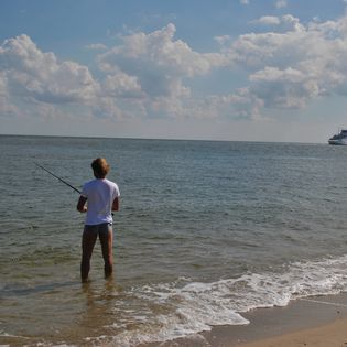 Ein Mann steht am Ellenbogen und angelt.