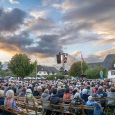 Open-Air-Kulturabend beim Verdensballett auf Sylt Freiluft-Veranstaltung mit Publikum vor reetgedeckten Häusern bei Sonnenuntergang