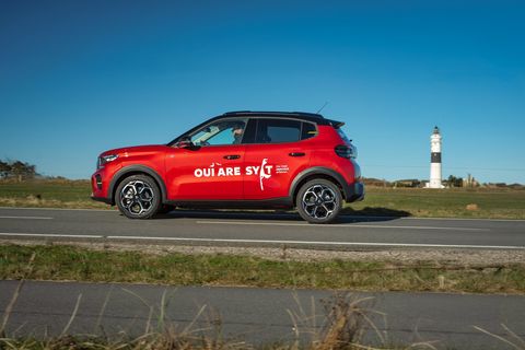 Rotes E-Auto vor Leuchtturm auf Sylt bei Sonnenschein