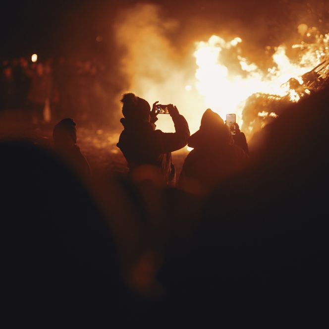 Menschen fotografieren ein großes Feuer bei Nacht mit ihren Handys