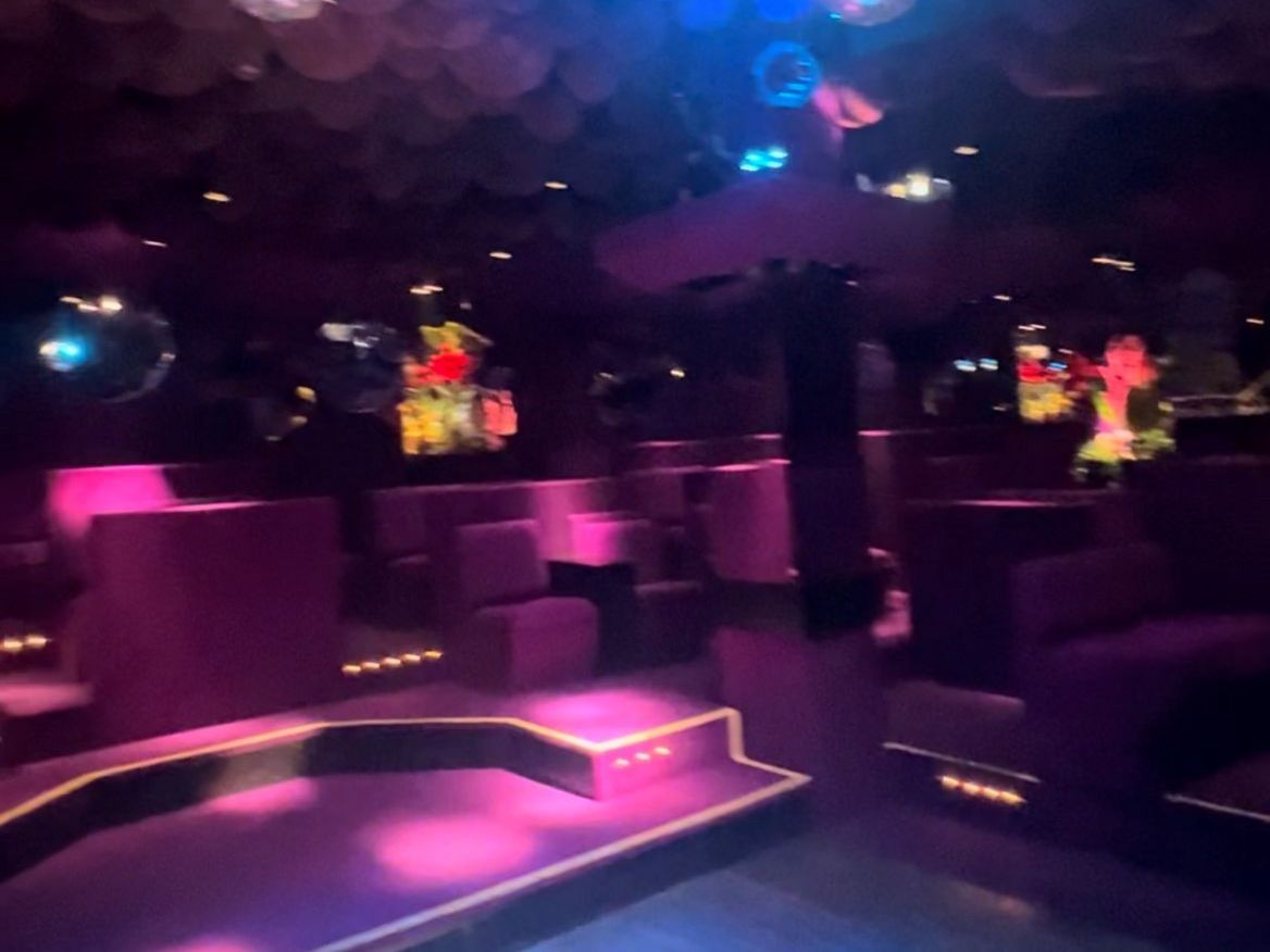 Leerer Club-Dancefloor mit violett-blauer Beleuchtung und hängenden Spiegelkugeln.