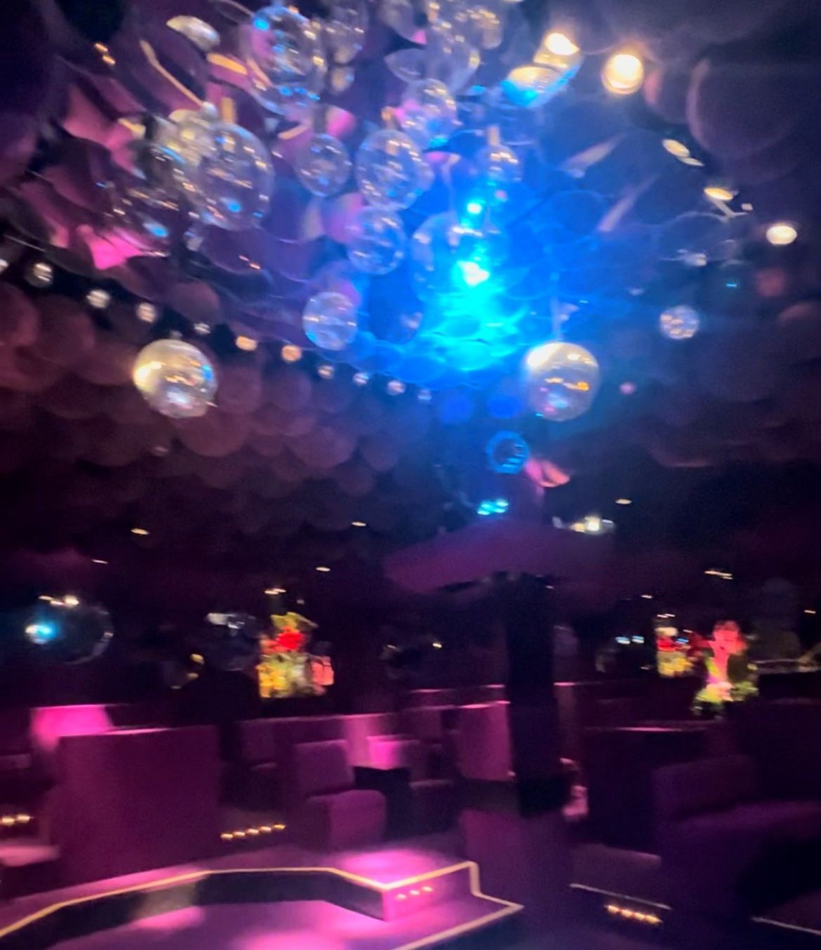 Leerer Club-Dancefloor mit violett-blauer Beleuchtung und hängenden Spiegelkugeln.