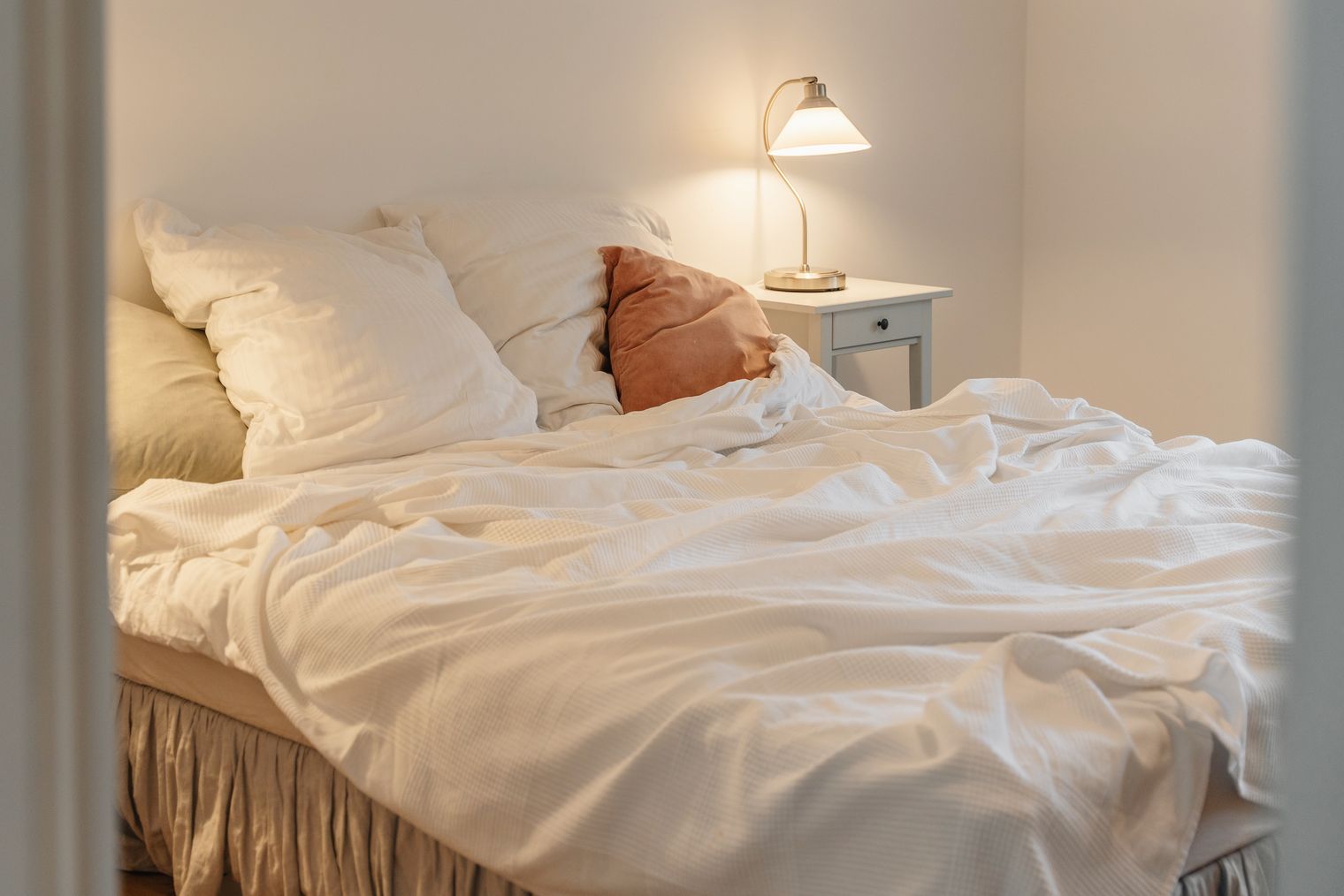 Gemachtes Bett mit Kissen und Lampe in hellem Schlafzimmer