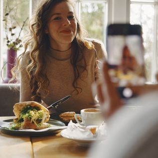 Genussmoment im Café: Lächeln, Kaffee und ein Schnappschuss