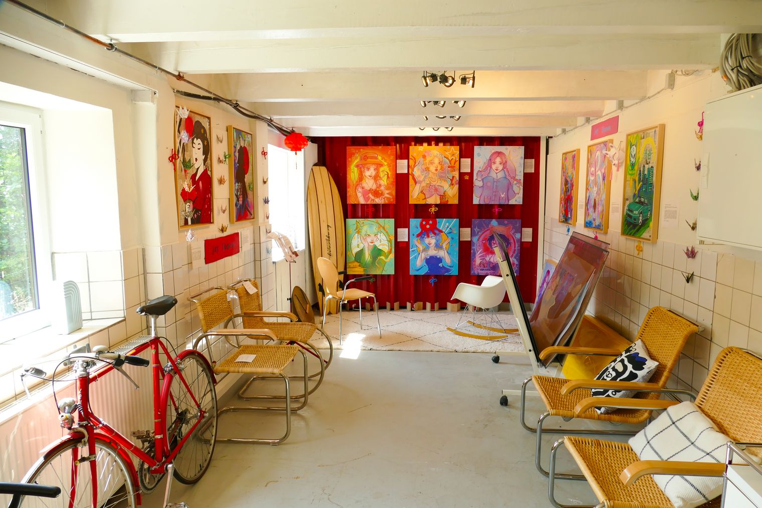 Galerieraum mit bunten Bildern, Fahrrädern und Stühlen