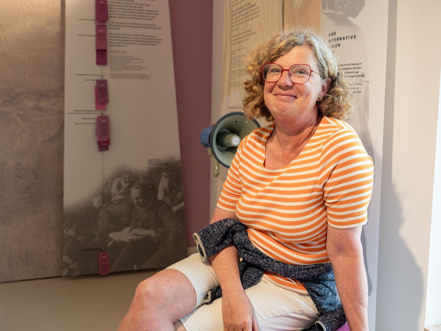 Frau sitzt lächelnd in der Ausstellung im Naturzentrum Braderup und schaut in die Kamera