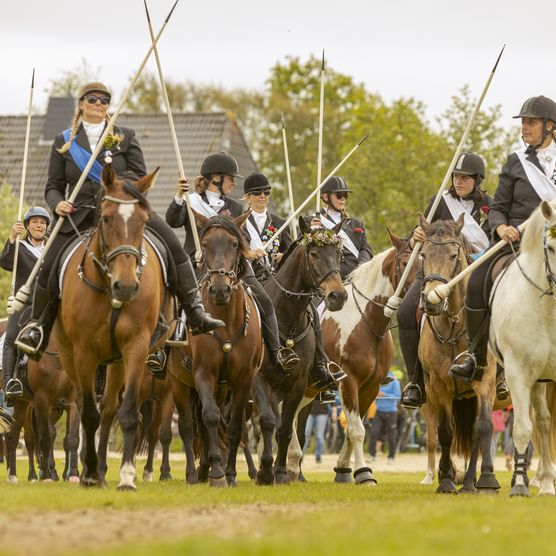 Reitergruppe mit festlicher Kleidung und Lanzen beim Ringreiten auf Sylt.