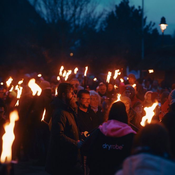 Menschenmenge mit brennenden Fackeln bei Abendveranstaltung in Tinnum