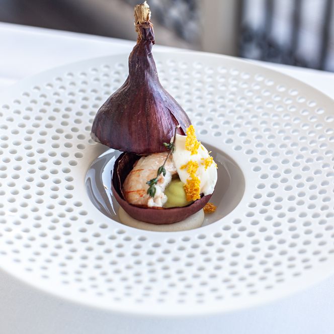 Kunstvoll angerichtetes Gourmetgericht mit Krustentier in roter Zwiebelschale beim Private Dining auf Sylt.