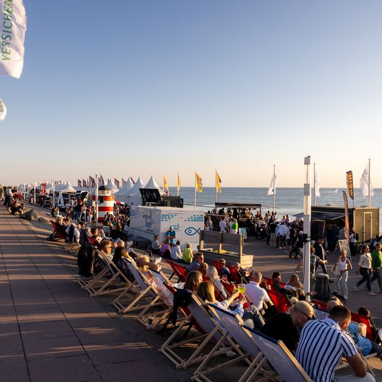 Besucher entspannen auf Liegestühlen an der Promenade