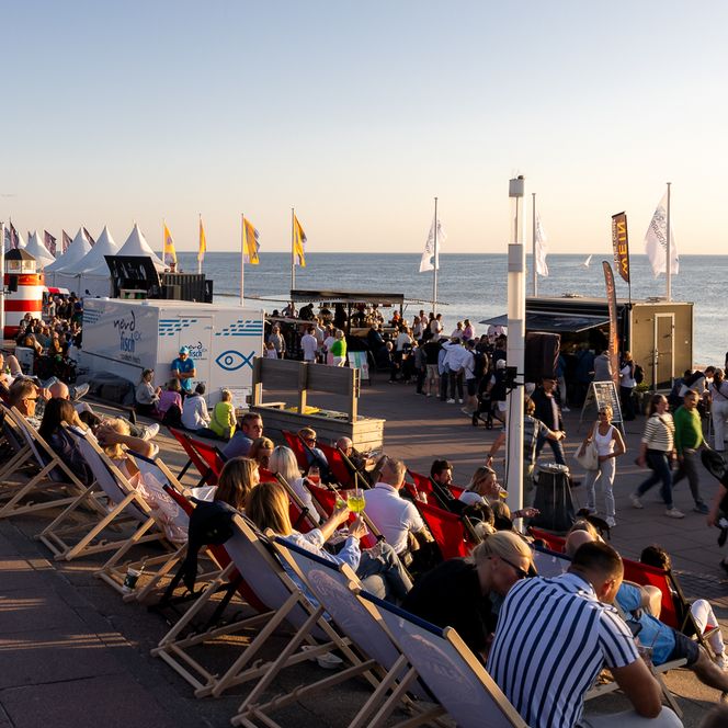 Besucher entspannen auf Liegestühlen an der Promenade