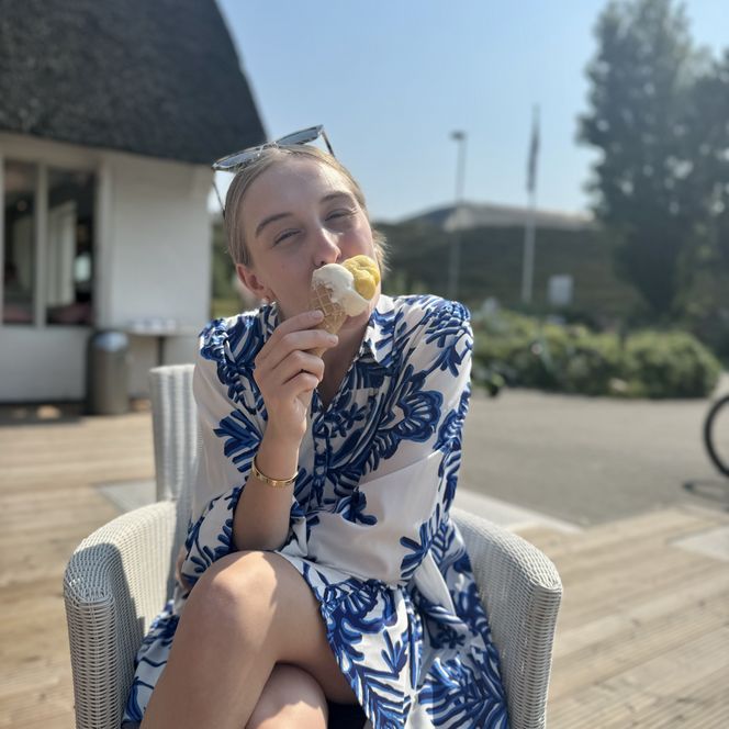 Frau sitzt im Freien und isst ein Eis in einer Waffel.