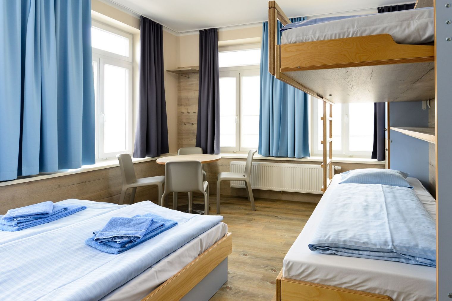 Helles Mehrbettzimmer mit Etagenbett, Einzelbett und Sitzecke