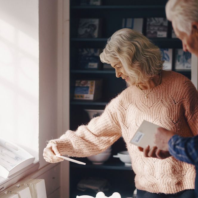 Älteres Paar entdeckt handgefertigte Kacheln in einem kleinen Laden Älteres Paar betrachtet dekorative Kacheln in einem sonnigen Laden.
