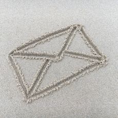 Ein in den Sand gezeichnetes Briefsymbol auf hellem Strand.