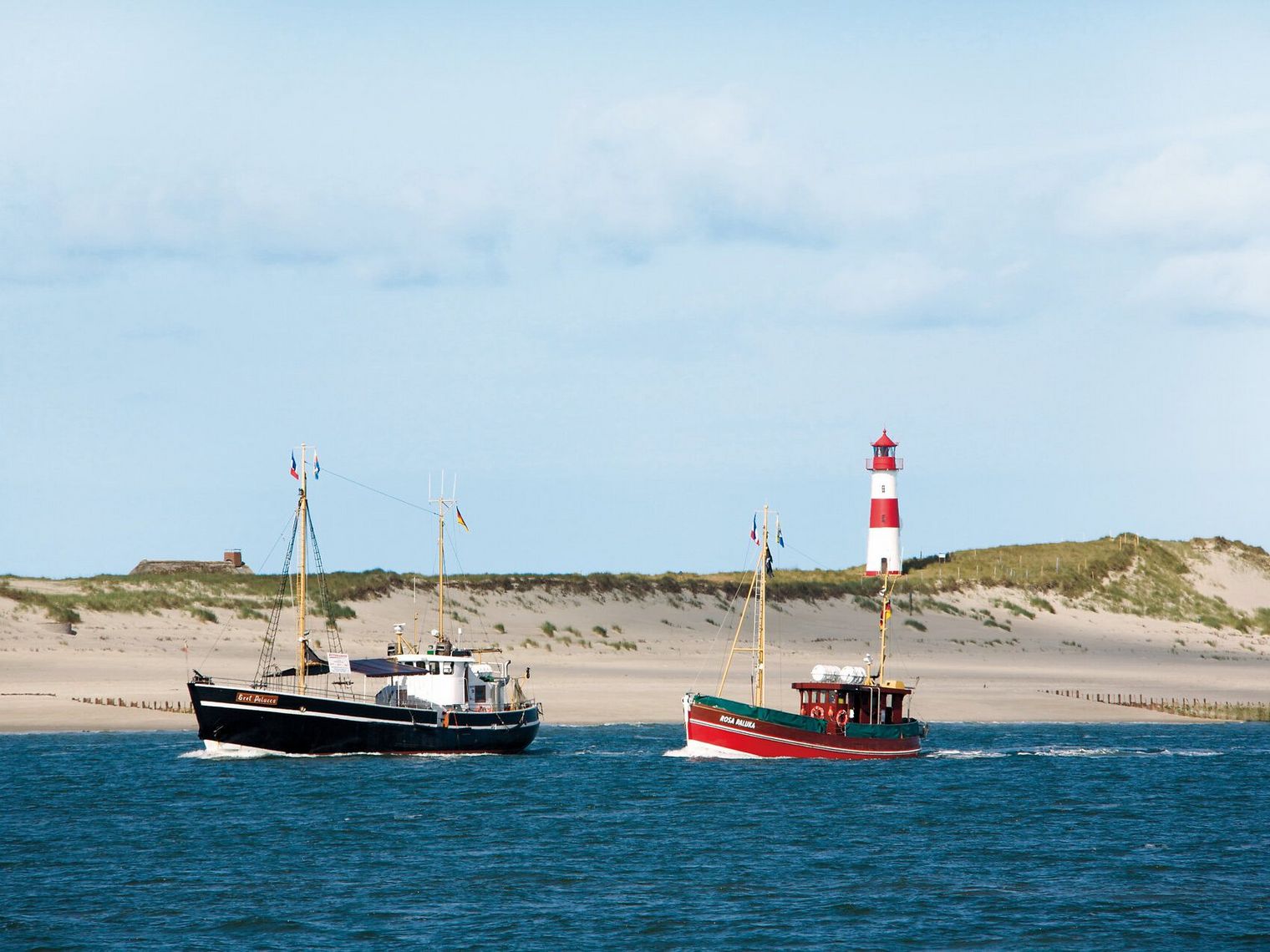Zwei Schiffe vor Dünen und Leuchtturm