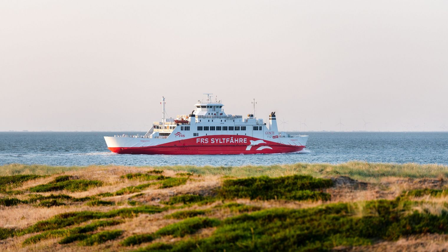 Die FRS Syltfähre Rømø Express gleitet sanft über das Wasser, während die Sonne das Wattenmeer in ein warmes Licht taucht. 