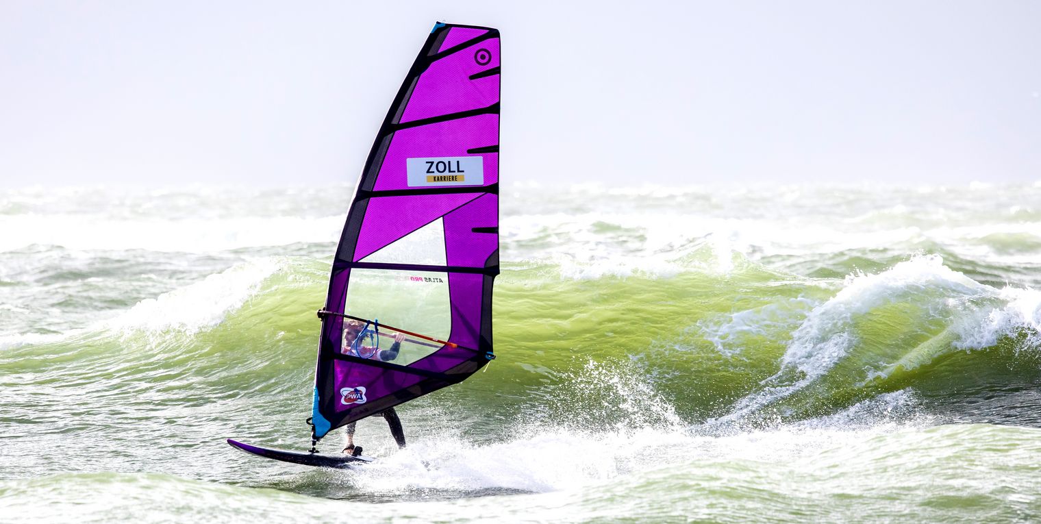 Windsurfer mit lila Segel in den Nordseewellen