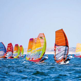 Windsurfer mit bunten Segeln im Wettkampf auf dem Meer