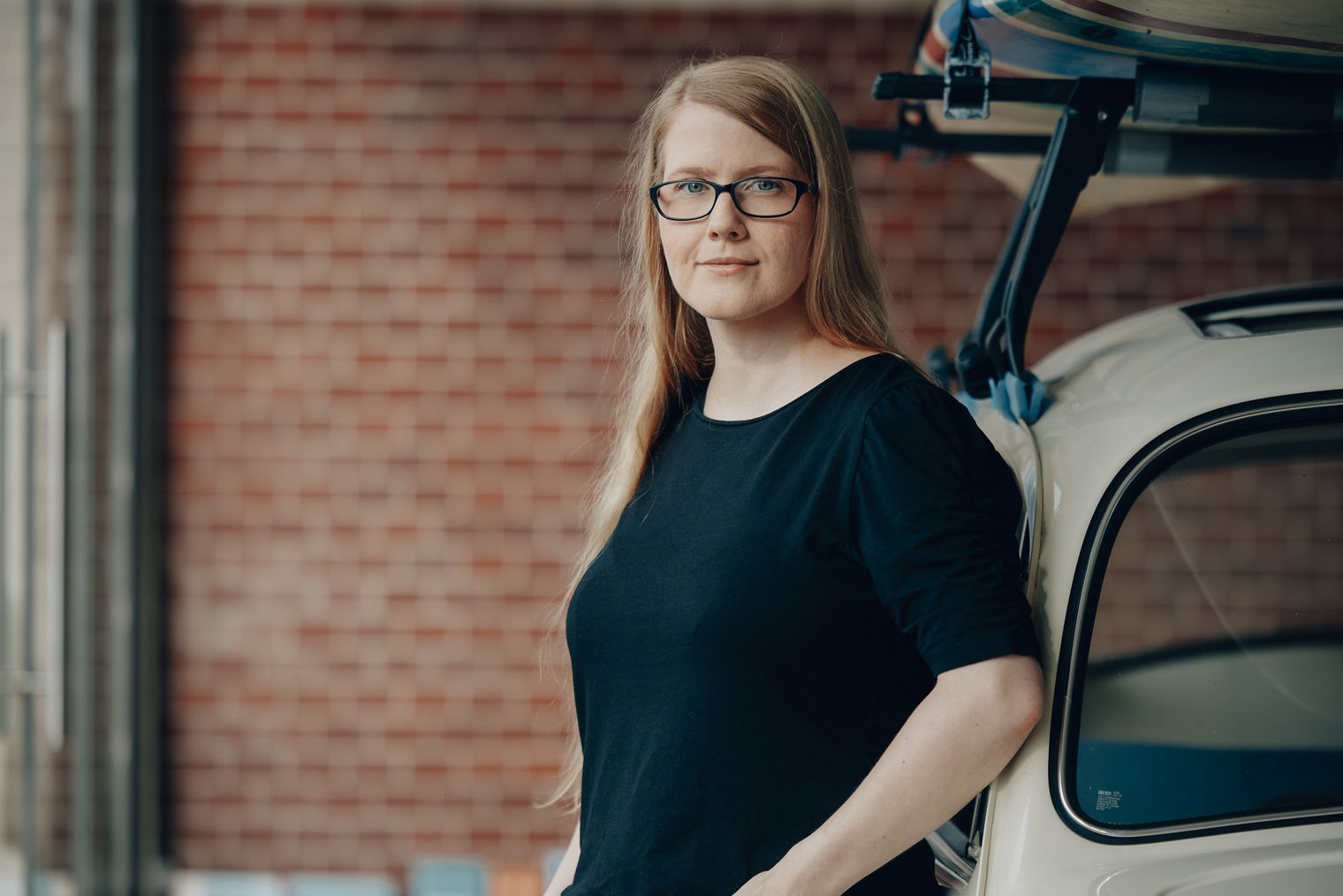 Martina Kramer von Sylt Marketing steht neben einem hellen Fahrzeug vor einer Backsteinwand.