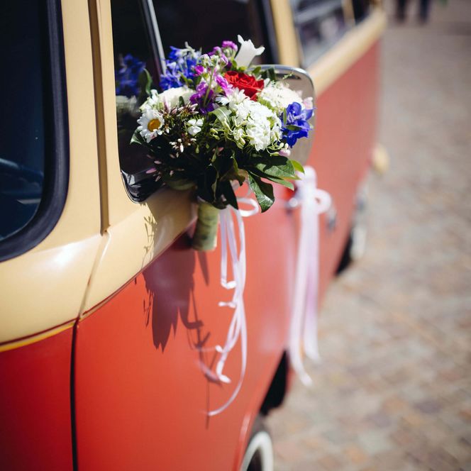 Blumenstrauß mit Schleifen am VW-Bulli bei Hochzeit